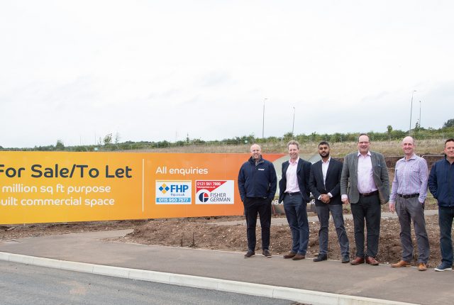 Fairham Business Park. 7 men stood by Fairham Business Park branded hoarding and a digger in the background