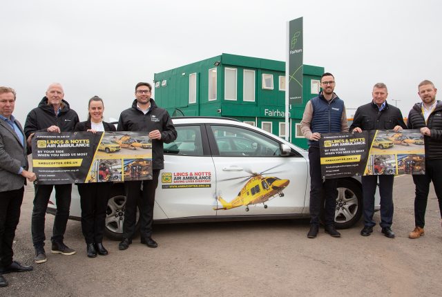 Fairham Business Park, Lincs and Notts air ambulance car and seven people holding two banners