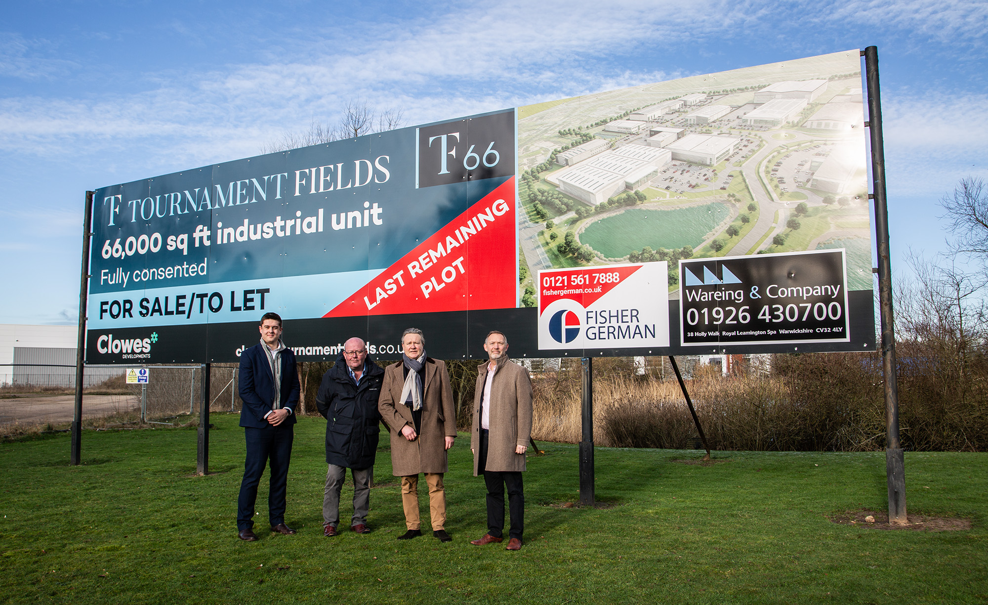 Tournament Fields, Plot TF66. Four men stood in front of a large advertising board, blue skies.