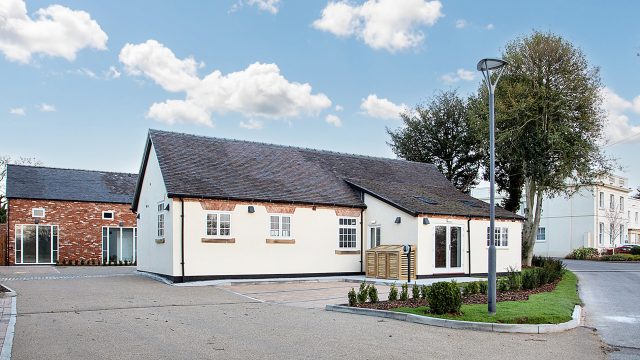 Ednaston Barns, The Byre unit. Cream building, car park and blue sky