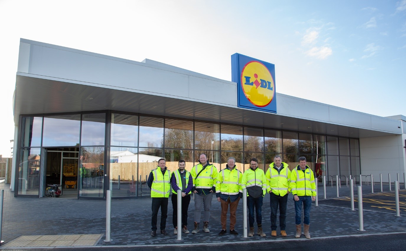 Stadium retail park, lidl shop with men stood outside in a line wearing high vis jackets.